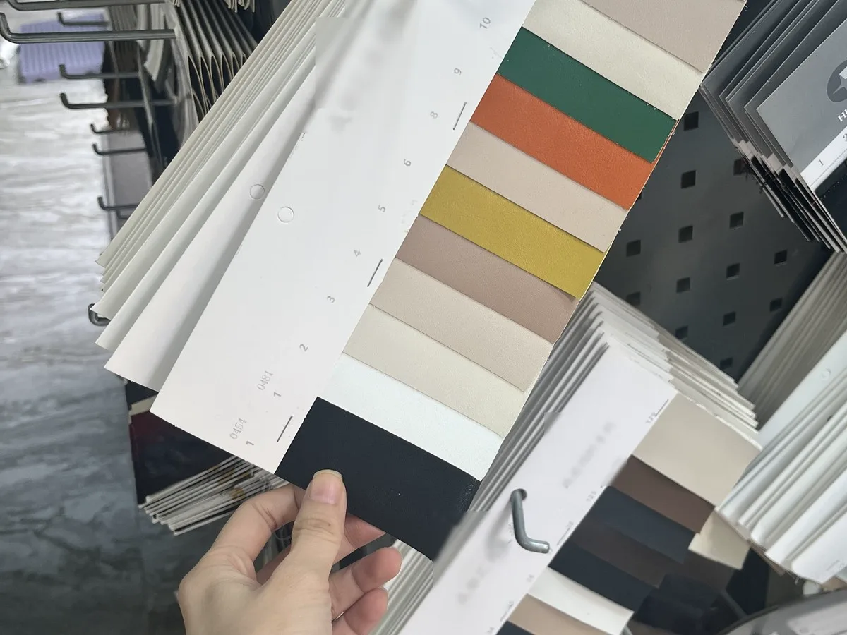 Hand flipping through leather color swatch cards at the material market near the Pandasoles shoe factory in Chengdu