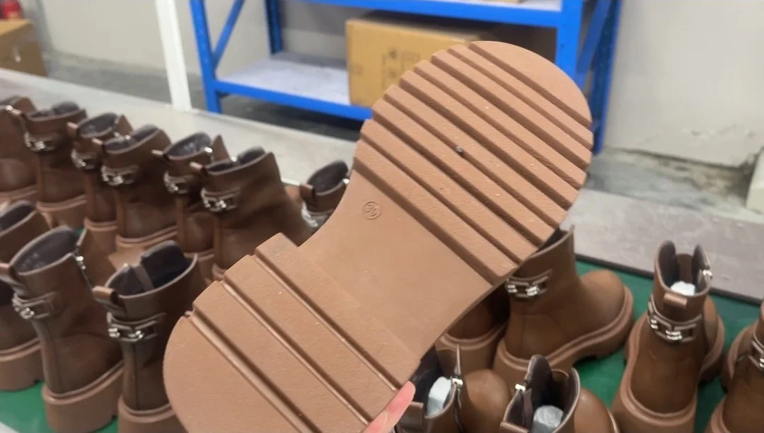 Close-up of a chunky rubber outsole on a brown ankle boot at the Pandasoles factory, checking tread and sole bonding