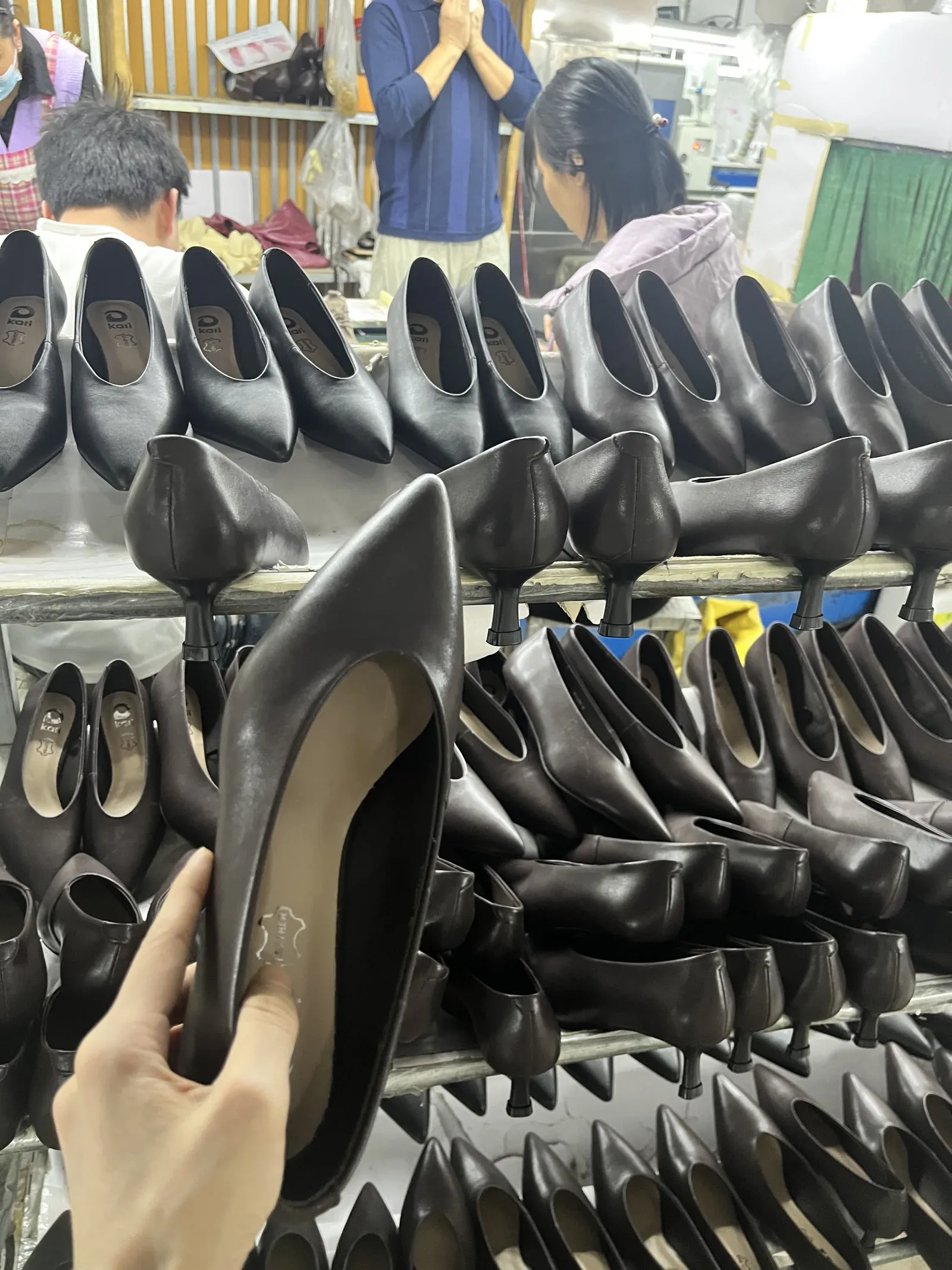 Finished brown leather pumps checked against racks of completed pairs before export packing