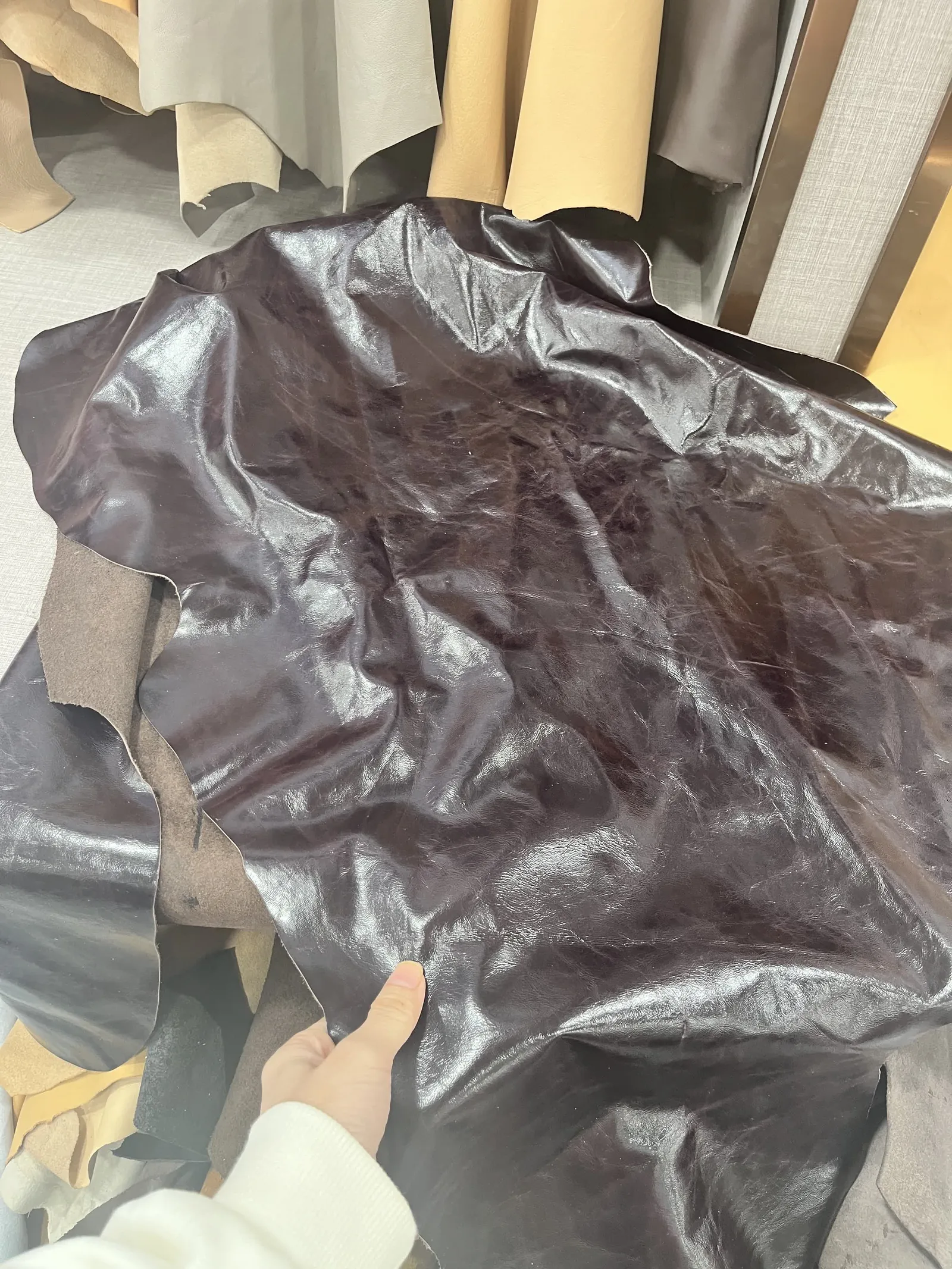 Hand checking the grain and finish of brown oil-waxed genuine leather at a materials market