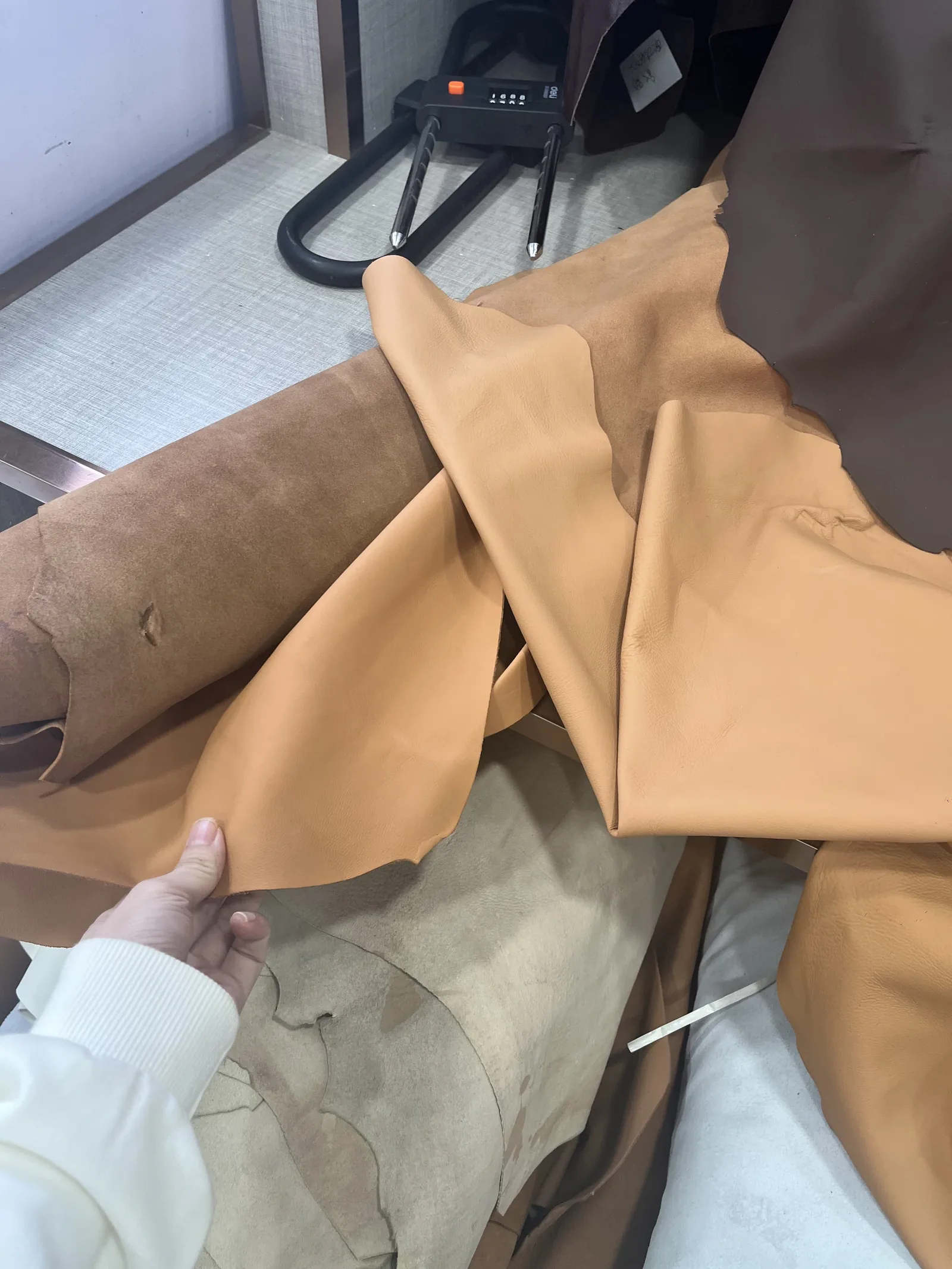 Hand checking the grain and softness of a black nappa cowhide hide at a leather shoe factory