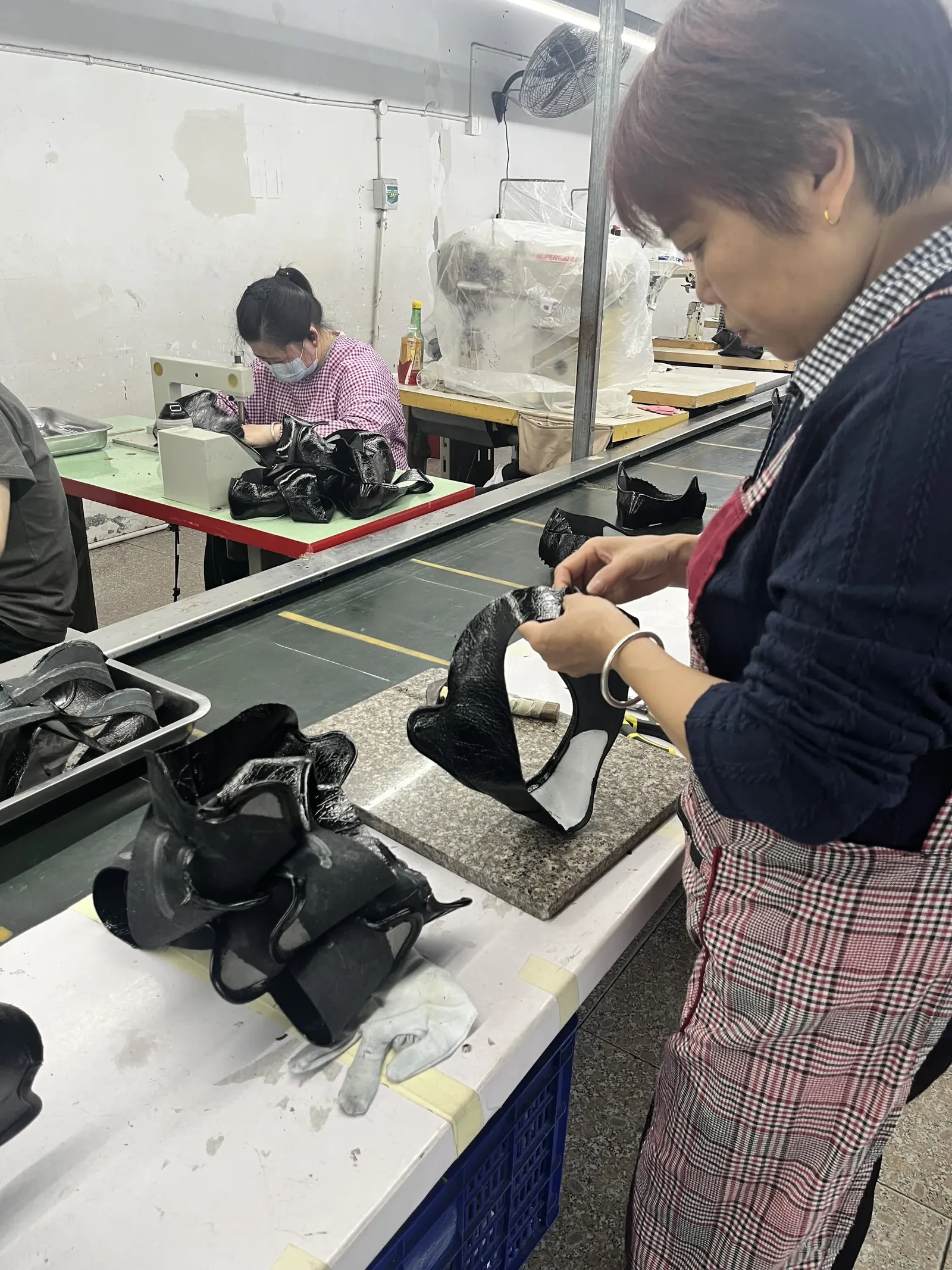 Workers at sewing stations on the production floor of the factory behind Pandasoles